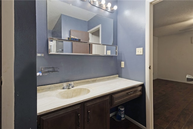 bathroom with hardwood / wood-style floors, vanity, and a textured ceiling