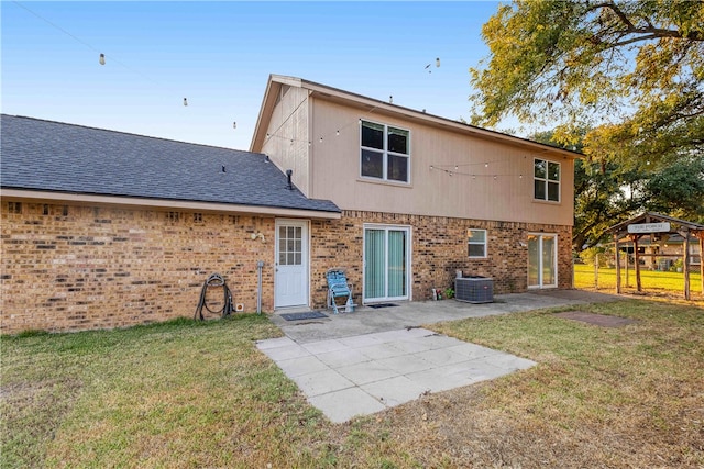 back of property with a lawn, central air condition unit, and a patio