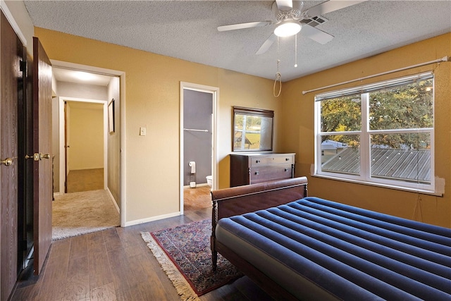 bedroom featuring ceiling fan, hardwood / wood-style floors, a textured ceiling, a walk in closet, and a closet