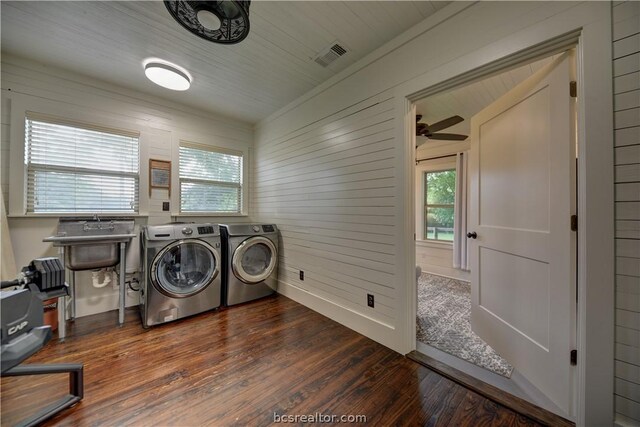 laundry room featuring washer and clothes dryer, a healthy amount of sunlight, wood walls, and dark wood-type flooring