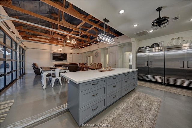 kitchen with gray cabinets, decorative light fixtures, a kitchen island, and concrete floors