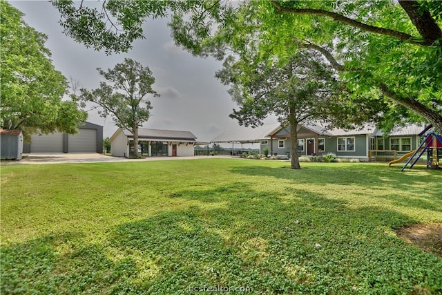 view of yard featuring a playground, an outdoor structure, and a garage