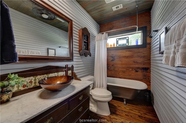 bathroom featuring a tub to relax in, vanity, wood-type flooring, toilet, and wood walls