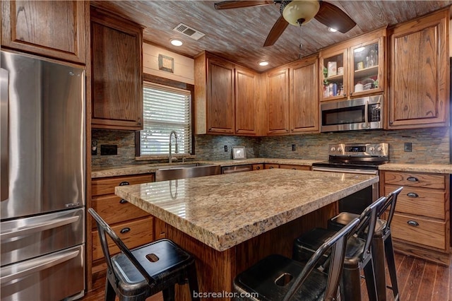 kitchen featuring a kitchen breakfast bar, sink, dark wood-type flooring, and appliances with stainless steel finishes