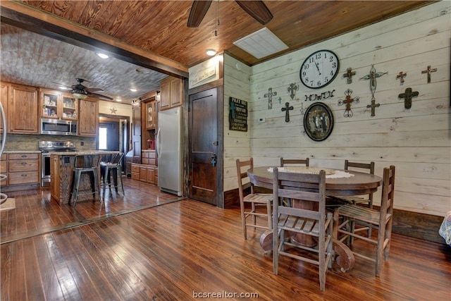 dining room featuring wooden walls, dark hardwood / wood-style flooring, ceiling fan, and wooden ceiling