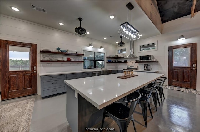 kitchen with pendant lighting, gray cabinetry, sink, appliances with stainless steel finishes, and a breakfast bar area