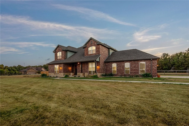 view of front of home with a yard, brick siding, and roof with shingles