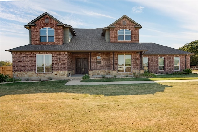 view of front of home with a front yard, brick siding, and roof with shingles