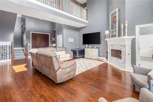 living room with hardwood / wood-style floors, baseboards, a high end fireplace, stairs, and a towering ceiling