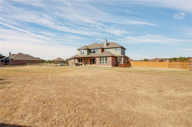 view of front of house with a front yard, fence, brick siding, and a chimney