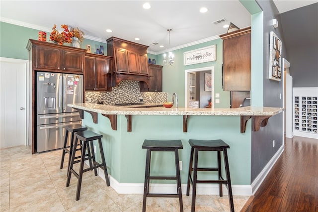 kitchen with visible vents, decorative backsplash, stainless steel refrigerator with ice dispenser, and crown molding