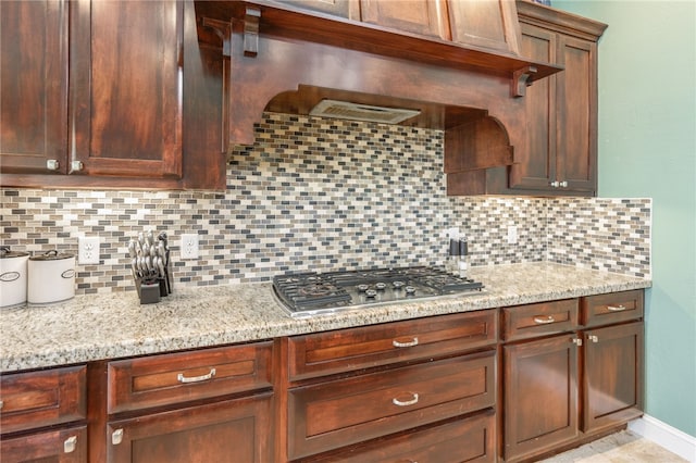 kitchen with decorative backsplash, light stone countertops, and stainless steel gas cooktop