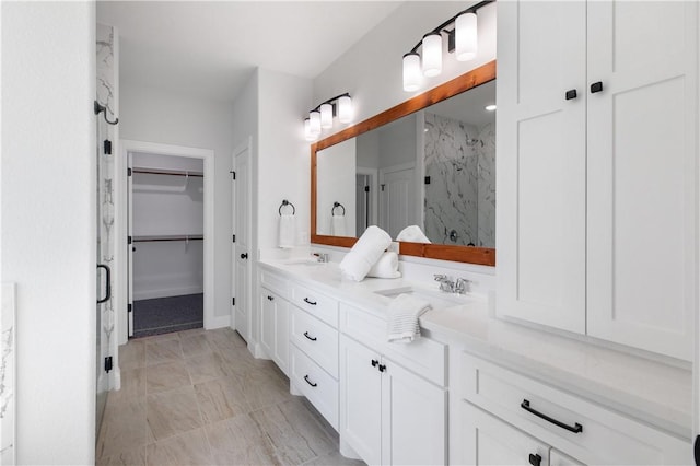 full bathroom with a sink, a spacious closet, a marble finish shower, and double vanity