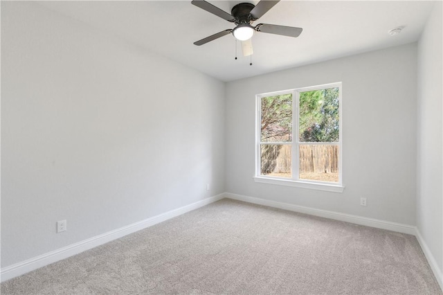 spare room with baseboards, a ceiling fan, and light colored carpet