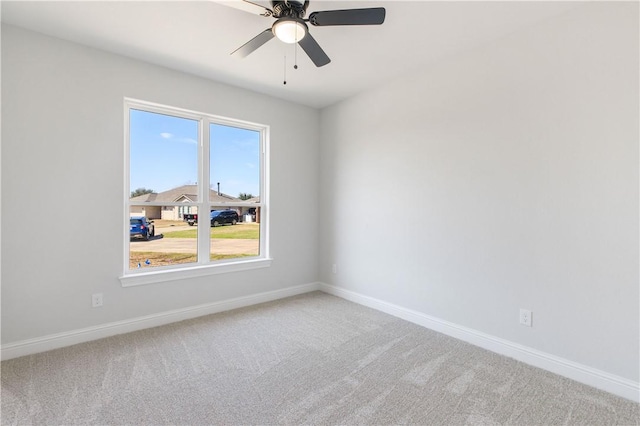 carpeted empty room featuring baseboards and a ceiling fan