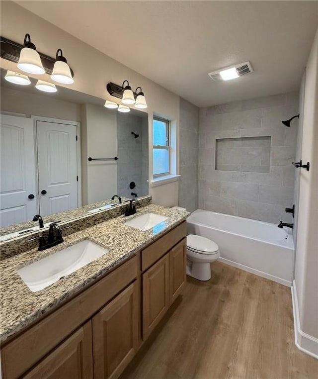 full bathroom featuring vanity, hardwood / wood-style flooring, toilet, and tiled shower / bath combo