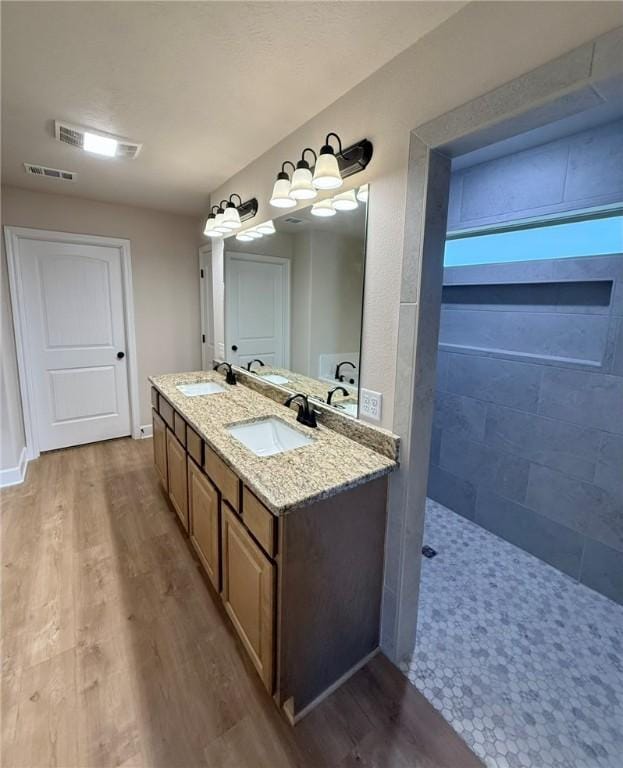 bathroom featuring vanity, wood-type flooring, and a tile shower