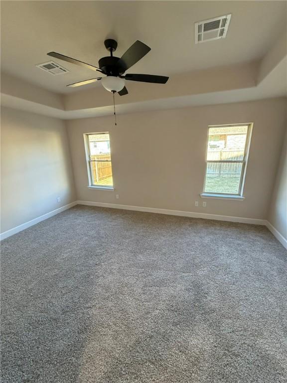 carpeted empty room with ceiling fan and a tray ceiling