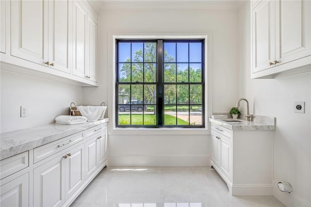 laundry room with a wealth of natural light, hookup for an electric dryer, baseboards, and a sink