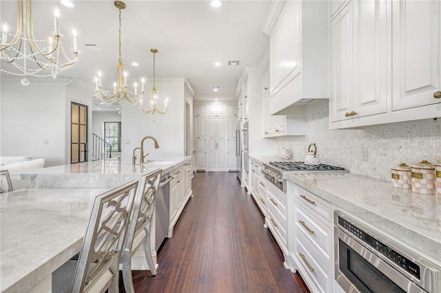 kitchen featuring white cabinets, a sink, dark wood-style flooring, appliances with stainless steel finishes, and a chandelier