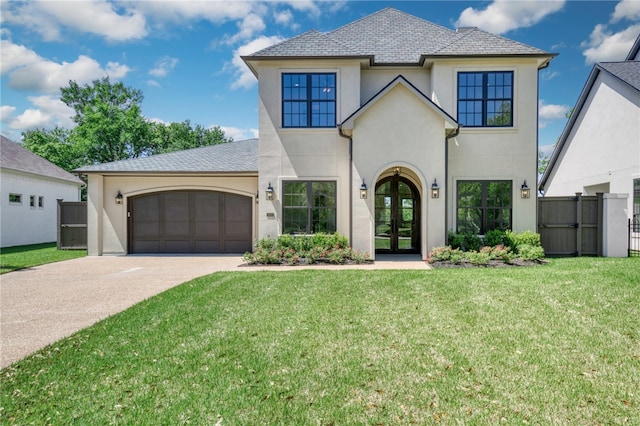 view of front of house with a front yard, an attached garage, stucco siding, french doors, and driveway