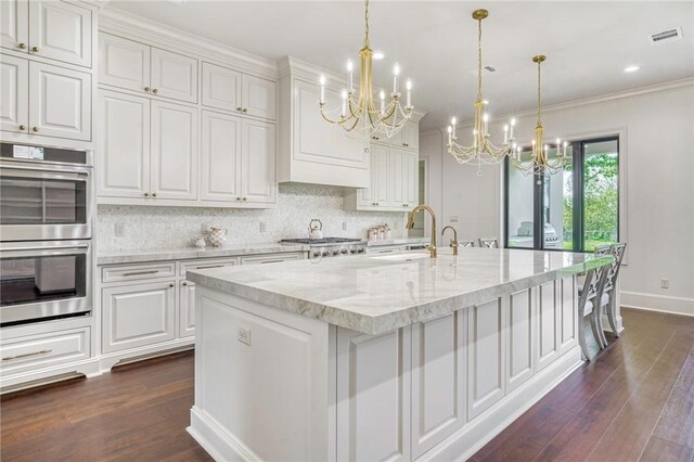 kitchen with an inviting chandelier, double oven, dark wood-style flooring, a sink, and backsplash