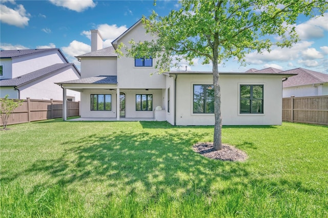back of property featuring a fenced backyard, a lawn, and stucco siding