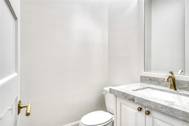 bathroom featuring toilet, vanity, and baseboards