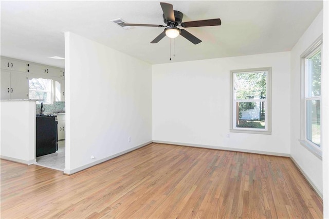 spare room featuring ceiling fan, light hardwood / wood-style floors, and a wealth of natural light