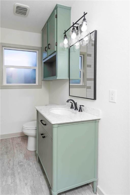 bathroom with wood-type flooring, vanity, and toilet