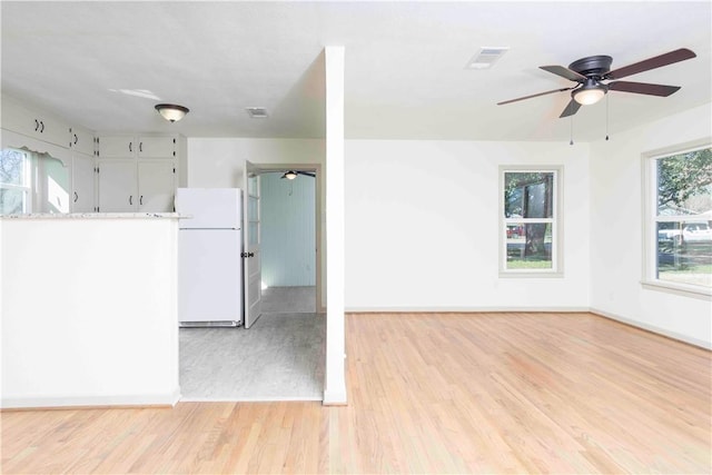 kitchen featuring white refrigerator, light hardwood / wood-style floors, and white cabinetry