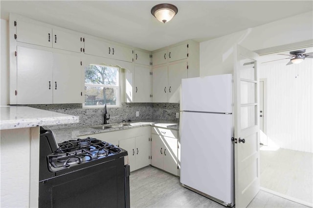 kitchen with white cabinets, white fridge, black range with gas cooktop, and sink