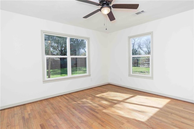 spare room with wood-type flooring, a wealth of natural light, and ceiling fan