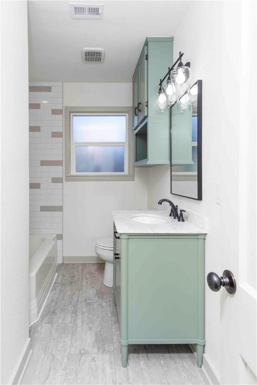 full bathroom featuring tiled shower / bath, vanity, and toilet