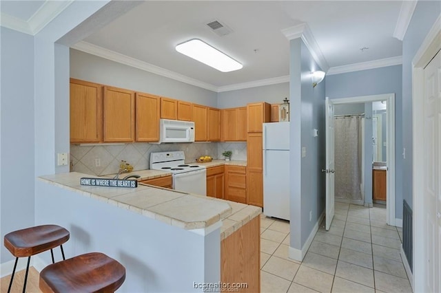 801 Luther St W Unit 407, College Station, TX 77840 - kitchen with white appliances, a peninsula, light countertops, a kitchen bar, and tasteful backsplash
