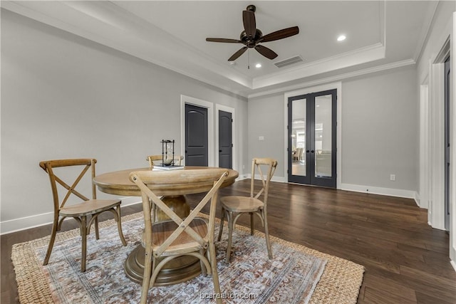 dining area featuring french doors, dark hardwood / wood-style flooring, ornamental molding, a tray ceiling, and ceiling fan