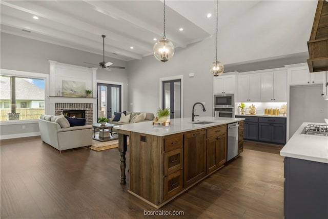 kitchen featuring sink, dark wood-type flooring, stainless steel appliances, a kitchen island with sink, and white cabinets