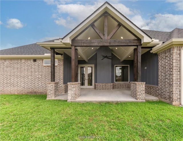 rear view of property featuring a lawn, ceiling fan, and french doors