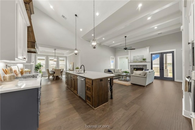 kitchen featuring french doors, dishwasher, a center island with sink, and decorative light fixtures