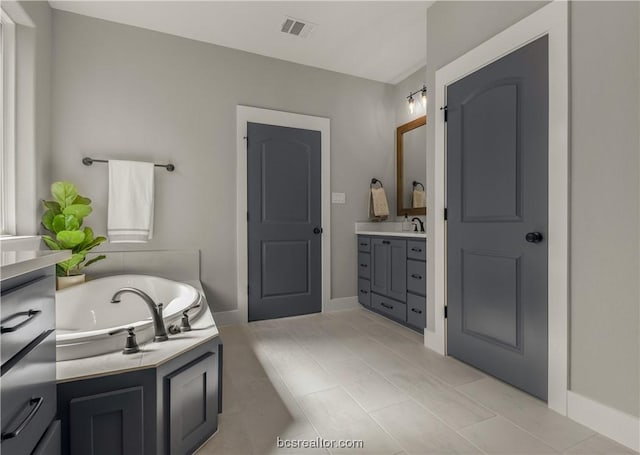 bathroom featuring tile patterned floors, vanity, and a tub to relax in