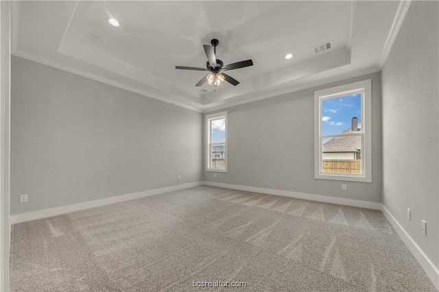 unfurnished room with a raised ceiling, crown molding, carpet floors, and ceiling fan