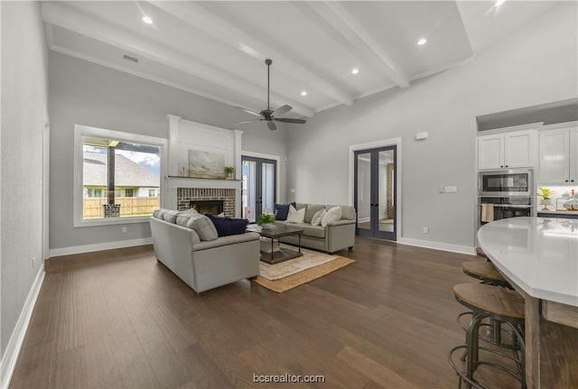 living room featuring french doors, a brick fireplace, ceiling fan, beamed ceiling, and dark hardwood / wood-style flooring