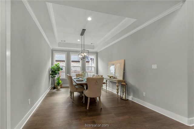 dining area featuring a tray ceiling, dark hardwood / wood-style flooring, a notable chandelier, and ornamental molding