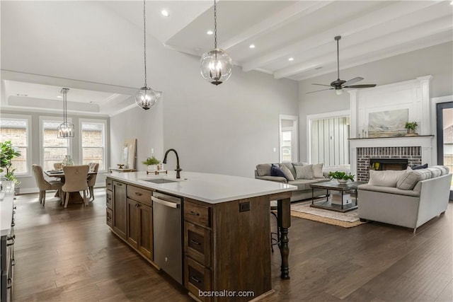 kitchen with stainless steel dishwasher, decorative light fixtures, sink, and an island with sink