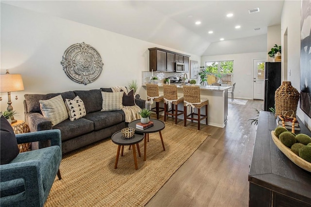 living room featuring light hardwood / wood-style floors and vaulted ceiling