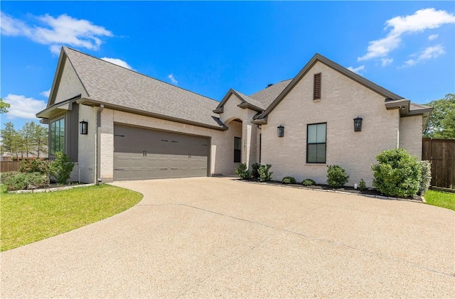 1701 Kerr Valley Ln, College Station, TX 77845 - french country inspired facade with roof with shingles, concrete driveway, an attached garage, and brick siding