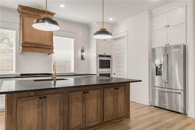 1701 Kerr Valley Ln, College Station, TX 77845 - kitchen featuring stainless steel appliances, light wood finished floors, pendant lighting, dark stone countertops, and a center island with sink