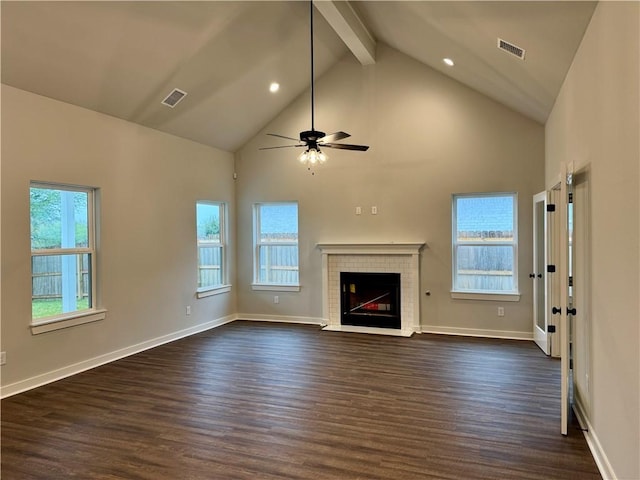 unfurnished living room with plenty of natural light, dark hardwood / wood-style floors, a tile fireplace, and high vaulted ceiling