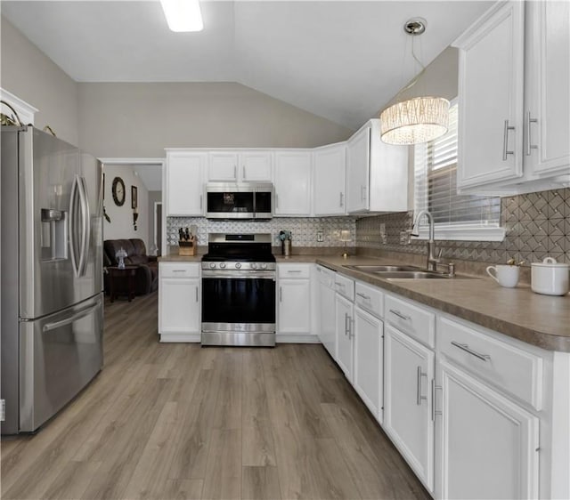 kitchen featuring a sink, stainless steel appliances, vaulted ceiling, light wood-style floors, and white cabinetry