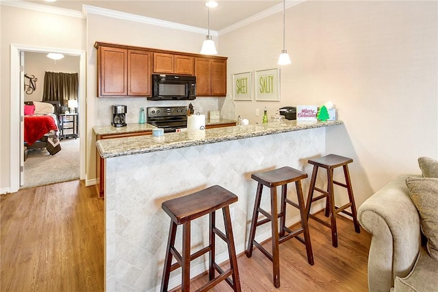 kitchen with kitchen peninsula, light stone counters, black appliances, light hardwood / wood-style floors, and hanging light fixtures